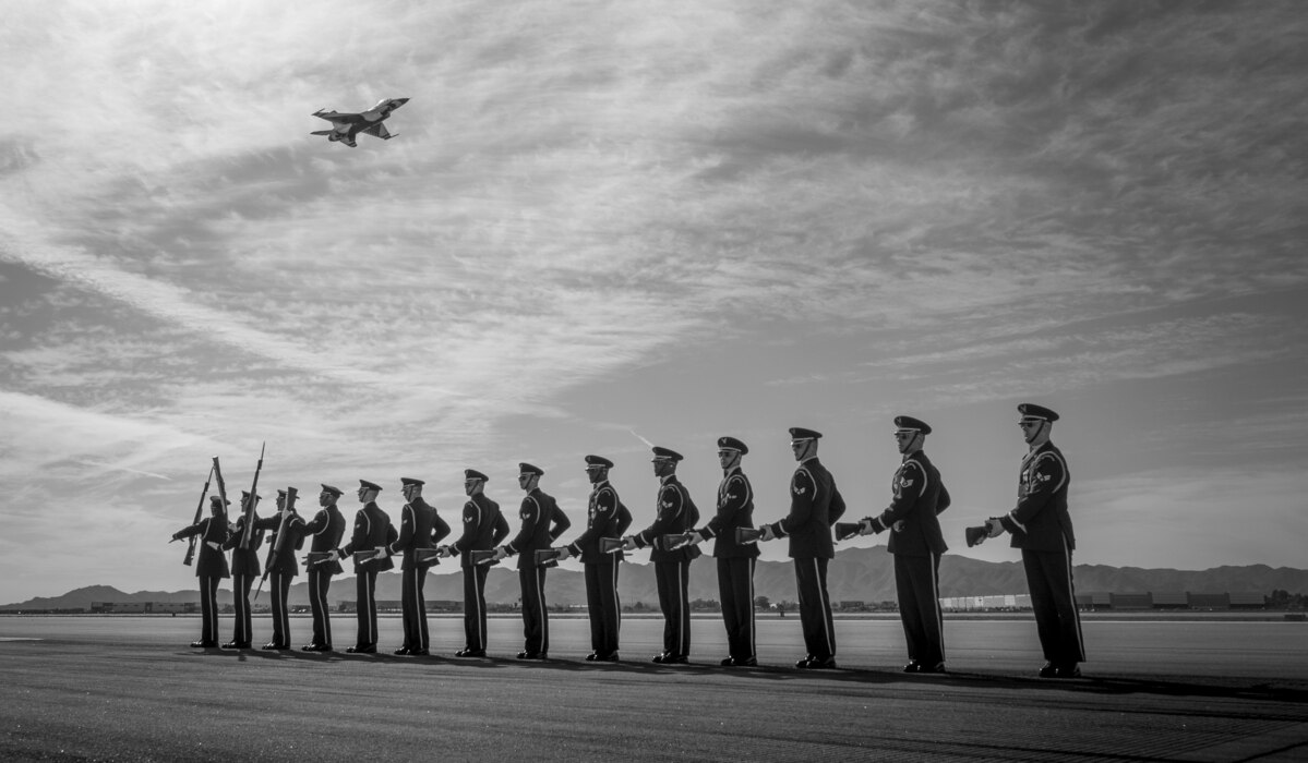 The U.S. Air Force Honor Guard practices a formation as an F-16 Fighting Falcon, assigned to the U.S. Air Force Demonstration team, the "Thunderbirds," pass behind them prior to Luke Days 2024 on March 22, 2024, at Luke Air Force Base, Arizona.