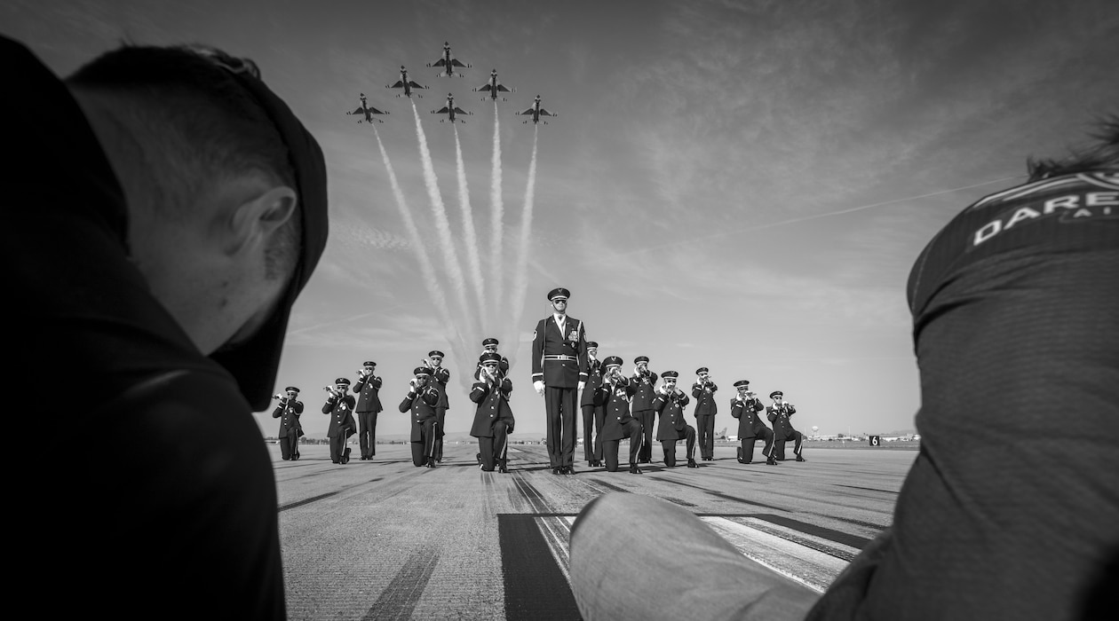 The U.S. Air Force Honor Guard stands in formation as F-16 Fighting Falcons, assigned to the U.S. Air Force Demonstration team, the "Thunderbirds," pass above them prior to Luke Days 2024 on March 22, 2024, at Luke Air Force Base, Arizona.