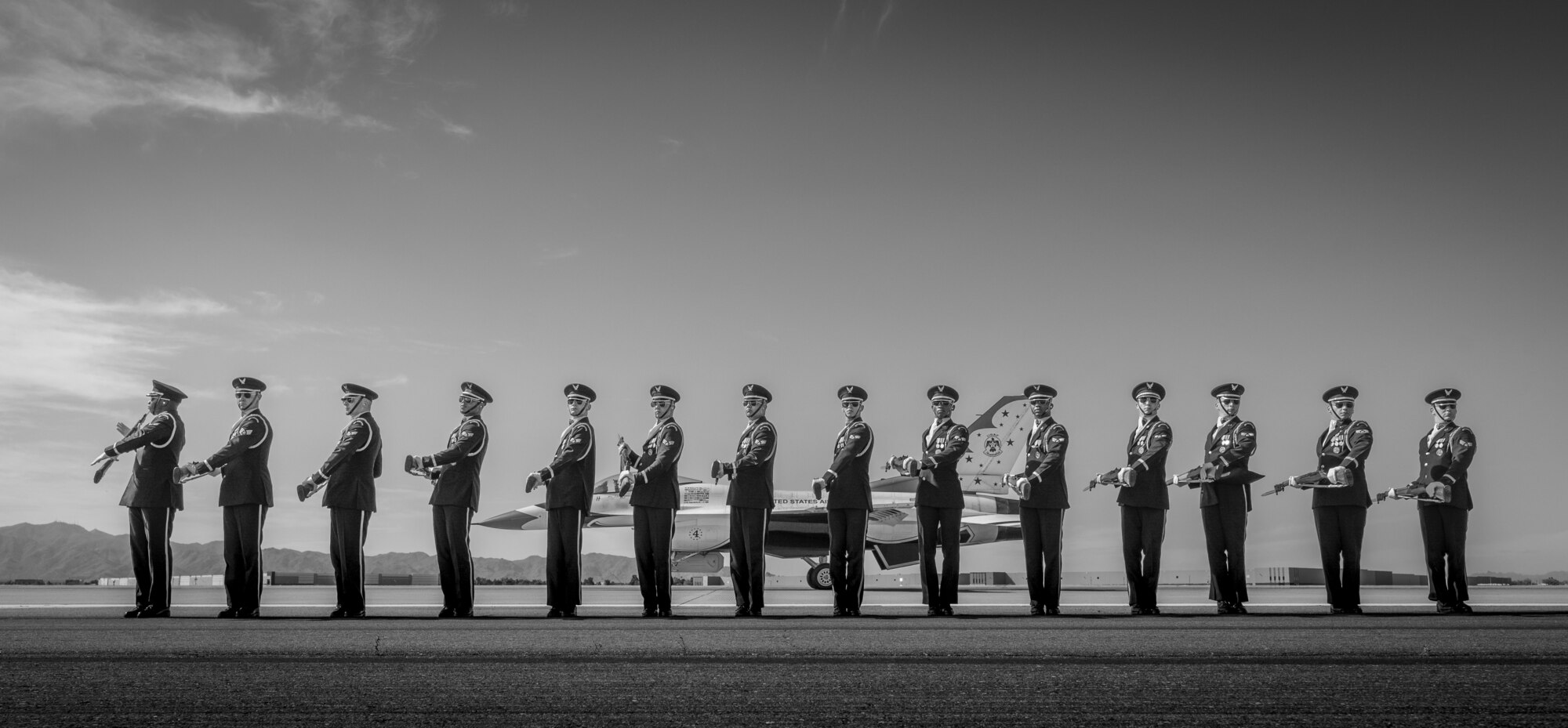 The U.S. Air Force Honor Guard practices a formation as an F-16 Fighting Falcon, assigned to the U.S. Air Force Demonstration team, the "Thunderbirds," pass behind them prior to Luke Days 2024 on March 22, 2024, at Luke Air Force Base, Arizona.