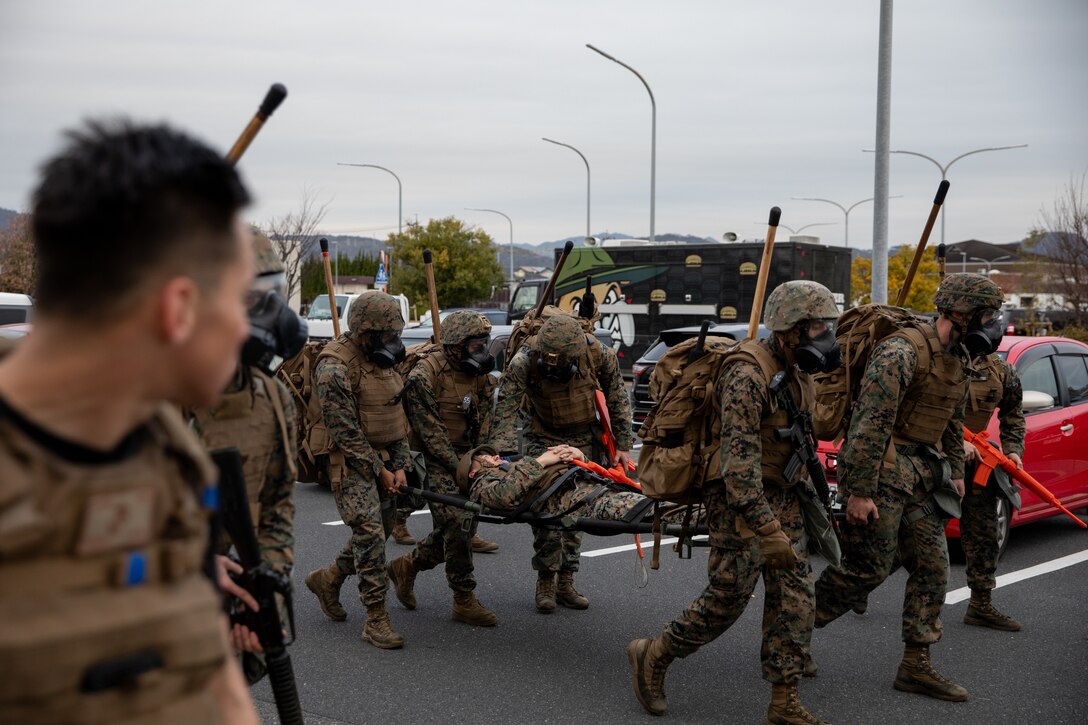 U.S. Marines stationed at Marine Corps Air Station Iwakuni move a simulated casualty during the culminating event of a Marine Corps martial arts instructor course at MCAS Iwakuni, Japan, Dec. 14, 2023. Graduates of the 15-day course become qualified Martial Arts Instructors, empowered to independently lead and facilitate courses, assisting lower-belt Marines in their progression towards higher belts. (U.S. Marine Corps photo by Lance Cpl. Colin Thibault)