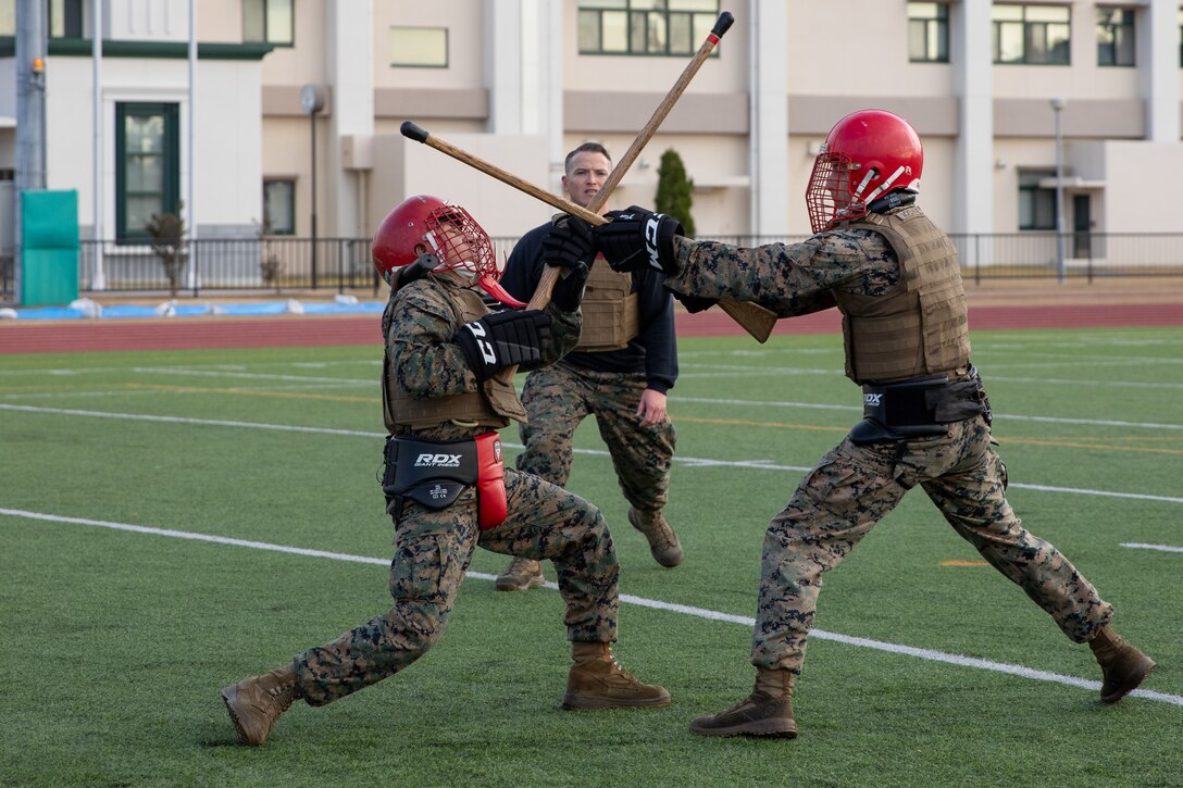 U.S. Marine Corps Cpls. Johnathan Culcayveletanga, left, and Richard Mckelvian, right, air traffic controllers with Headquarters and Headquarters Squadron, Marine Corps Air Station Iwakuni, spar with wooden rifles during the culminating event of a Marine Corps martial arts instructor course at MCAS Iwakuni, Japan, Dec. 14, 2023. Graduates of the 15-day course become qualified Martial Arts Instructors, empowered to independently lead and facilitate courses, assisting lower-belt Marines in their progression towards higher belts. (U.S. Marine Corps photo by Lance Cpl. Colin Thibault)