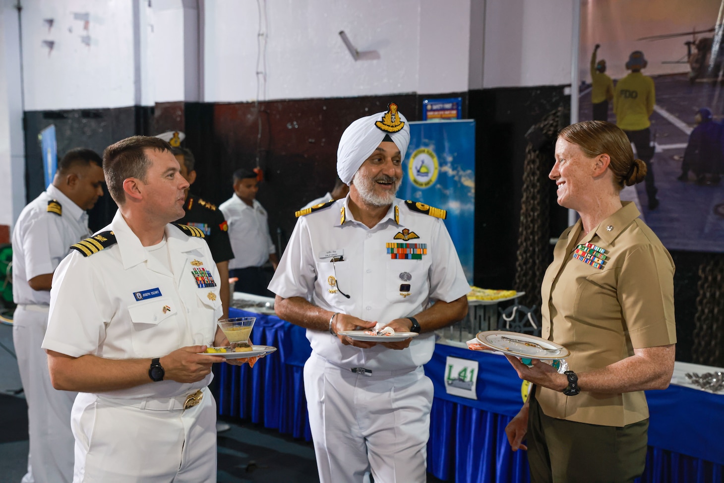 U.S. Marine Corps Lt. Col. Lindsay Mathwick, right, commanding officer of Combat Logistics Battalion 15, 15th Marine Expeditionary Unit, and the commander of troops aboard the amphibious transport dock USS Somerset (LPD 25), enjoys local Indian hors d’oeuvres with Cmdr. Joseph Cozart, left, assistant chief of staff for logistics, Expeditionary Strike Group 7 and Task Force 76/3, and Commodore Dalip Singh, commanding officer of Naval Air Station INS Dega, center, during the opening ceremony of Exercise Tiger TRIUMPH in Visakhapatnam, India, March 19, 2024. Tiger TRIUMPH is a U.S.-India tri-service amphibious exercise focused on humanitarian assistance and disaster relief readiness and interoperability. Tiger TRIUMPH enables U.S. and Indian Armed Forces to improve interoperability and bilateral, joint, and service readiness in the Indian Ocean region and beyond to better achieve mutual regional security objectives. (U.S. Marine Corps photo by Cpl. Aidan Hekker)