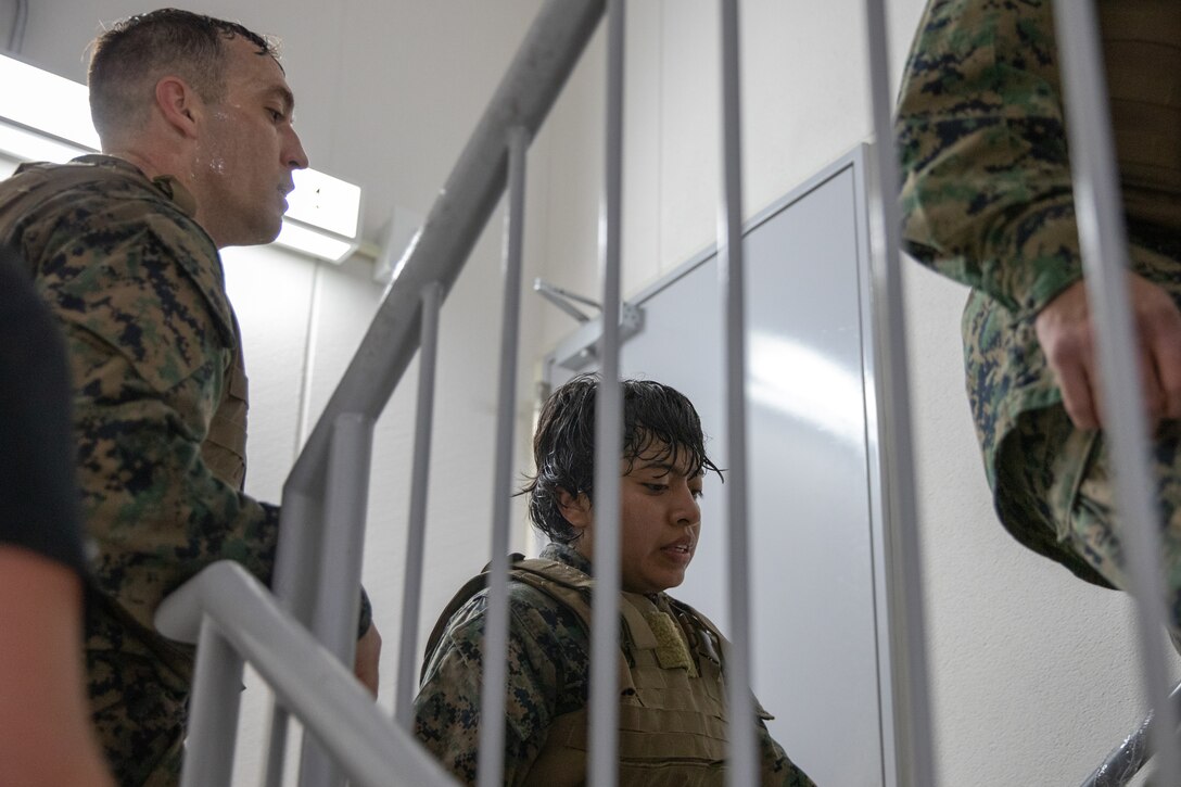U.S. Marine Corps Gunnery Sgt. Phillip Sandifer Jr, a senior air traffic controller with Headquarters and Headquarters Squadron, Marine Corps Air Station Iwakuni, left, and Cpl. Jessica GarciaLopez, a supply chain and materiel management specialist with Marine Aircraft Group 12, middle, climb stairs during the culminating event of a Marine Corps martial arts instructor course at MCAS Iwakuni, Japan, Dec. 14, 2023. Graduates of the 15-day course become qualified Martial Arts Instructors, empowered to independently lead and facilitate courses, assisting lower-belt Marines in their progression towards higher belts. (U.S. Marine Corps photo by Lance Cpl. Colin Thibault)