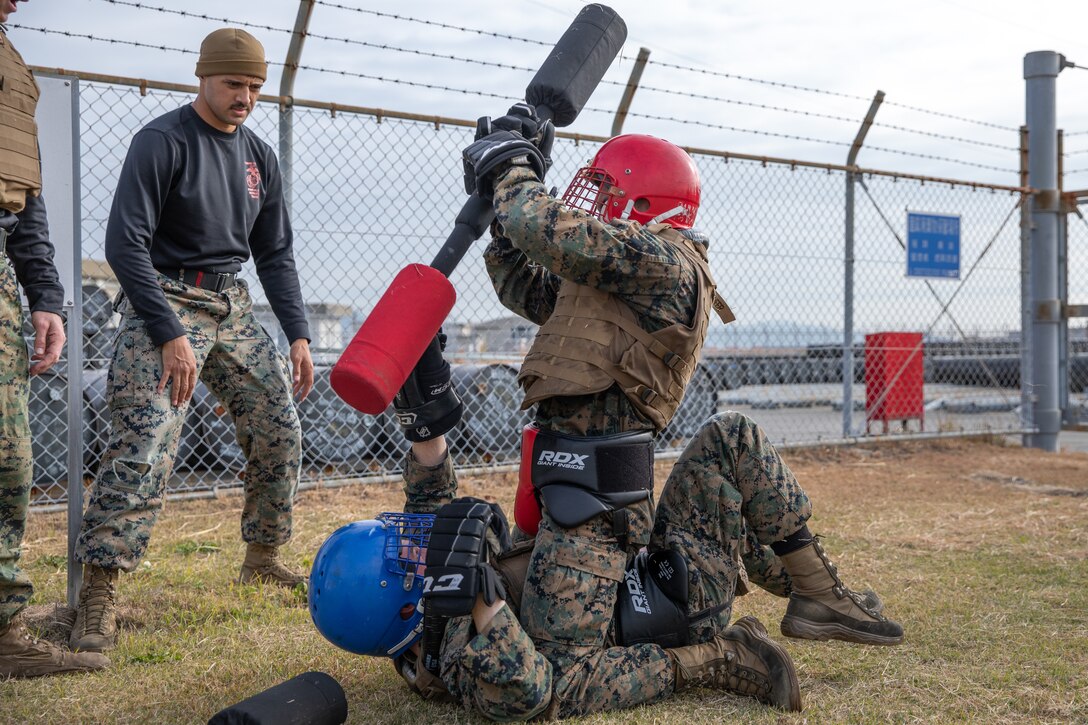 U.S. Marine Corps Gunnery Sgt. Phillip Sandifer Jr, a senior air traffic controller with Headquarters and Headquarters Squadron, Marine Corps Air Station Iwakuni, top, strikes Cpl. Zaedin Salerno, an aviation ground support equipment technician with Marine Aviation Logistics Squadron 11, with a pugil stick during the culminating event of a Marine Corps martial arts instructor course at MCAS Iwakuni, Japan, Dec. 14, 2023. Graduates of the 15-day course become qualified Martial Arts Instructors, empowered to independently lead and facilitate courses, assisting lower-belt Marines in their progression towards higher belts. (U.S. Marine Corps photo by Lance Cpl. Colin Thibault)