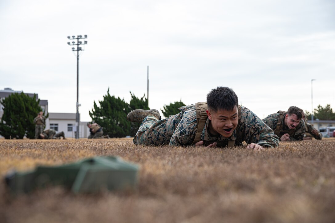 U.S. Marine Corps Sgt. Phuchung Nguyen, a combat photographer with Headquarters and Headquarters Squadron, Marine Corps Air Station Iwakuni, low crawls during the culminating event of a Marine Corps martial arts instructor course at MCAS Iwakuni, Japan, Dec. 14, 2023. Graduates of the 15-day course become qualified Martial Arts Instructors, empowered to independently lead and facilitate courses, assisting lower-belt Marines in their progression towards higher belts. (U.S. Marine Corps photo by Lance Cpl. Colin Thibault)