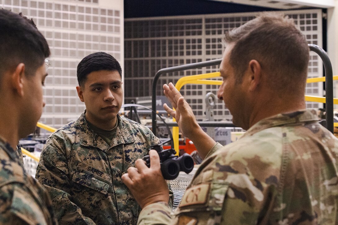 U.S. Air Force Tech. Sgt. Matthew Lothrop, an air transportation specialist with the U.S. Air Force 36th Contingency Response Squadron, 36th Contingency Response Group, right, shows U.S. Marine Corps Lance Cpl. Abel Gamez, a distribution management specialist with the Marine Corps Air Station Iwakuni Distribution Management Office, how to operate Gen III AN/AVS-9-night vision goggles during a training exercise at Marine Corps Air Station Iwakuni, Japan, Dec. 13, 2023.  The U.S. Air Force 36th Contingency Response Group conducted joint training that focused on equipment and process interoperability in a contested logistics environment with the MCAS Iwakuni Headquarters and Headquarters Squadron Logistics Department and members of the Japan Air Self-Defense Force.  (U.S. Marine Corps photo by Cpl. Darien Wright)