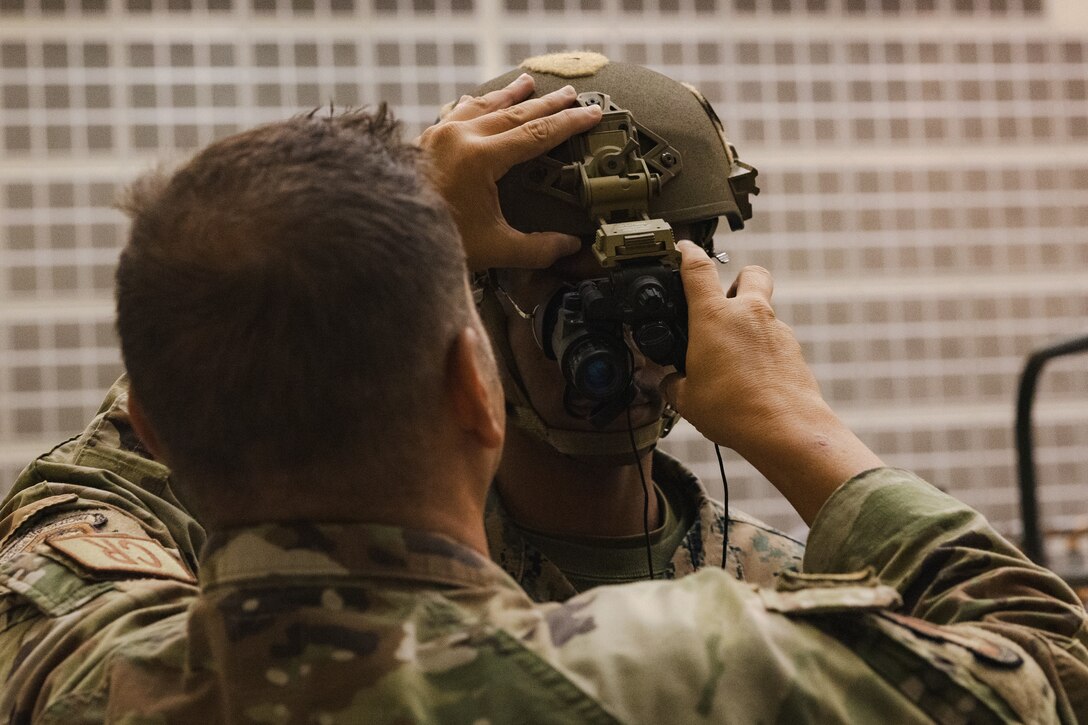 U.S. Air Force Tech. Sgt. Matthew Lothrop, an air transportation specialist with the U.S. Air Force 36th Contingency Response Squadron, 36th Contingency Response Group, left, assists U.S. Marine Corps Cpl. Kalonje Gordon, a distribution management specialist with the Marine Corps Air Station Iwakuni Distribution Management Office, equip a pair of Gen III AN/AVS-9 night vision goggles during a training exercise at Marine Corps Air Station Iwakuni, Japan, Dec. 13, 2023.  The U.S. Air Force 36th Contingency Response Group conducted joint training that focused on equipment and process interoperability in a contested logistics environment with the MCAS Iwakuni Headquarters and Headquarters Squadron Logistics Department and members of the Japan Air Self-Defense Force.  (U.S. Marine Corps photo by Cpl. Darien Wright)