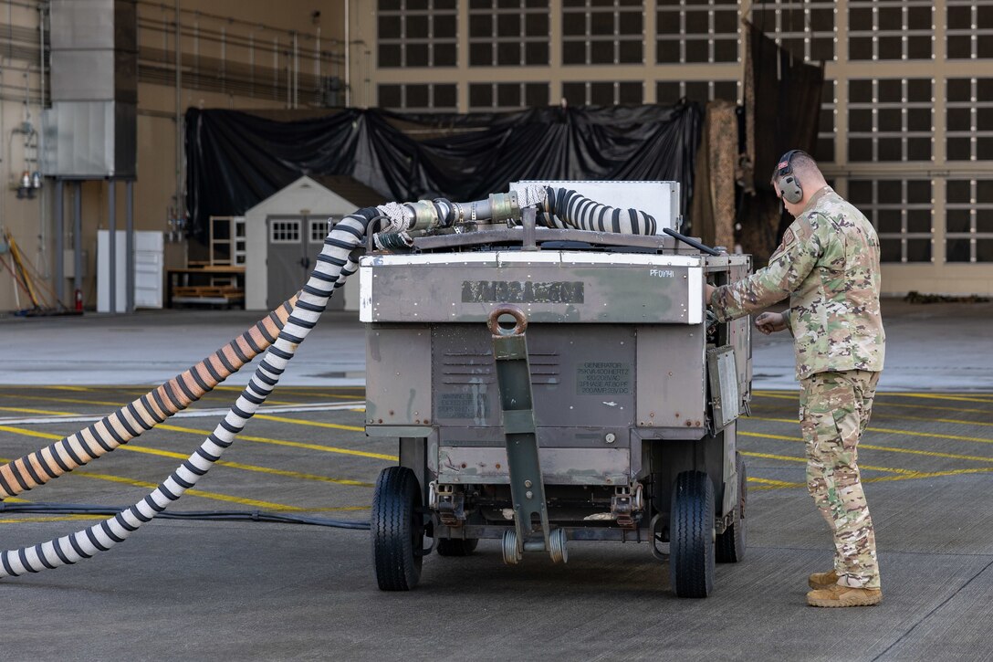 U.S. Air Force Staff Sgt. Ryan Merritt, an aerospace ground equipment specialist with the U.S. Air Force 36th Contingency Response Squadron, 36th Contingency Response Group, demonstrates how to operate an A/M32A-60A generator during a training exercise at MCAS Iwakuni, Japan, Dec. 12, 2023. The U.S. Air Force 36th Contingency Response Group conducted joint training that focused on equipment and process interoperability in a contested logistics environment with the MCAS Iwakuni Headquarters and Headquarters Squadron Logistics Department and members of the Japan Air Self-Defense Force.  (U.S. Marine Corps photo by Cpl. Darien Wright)