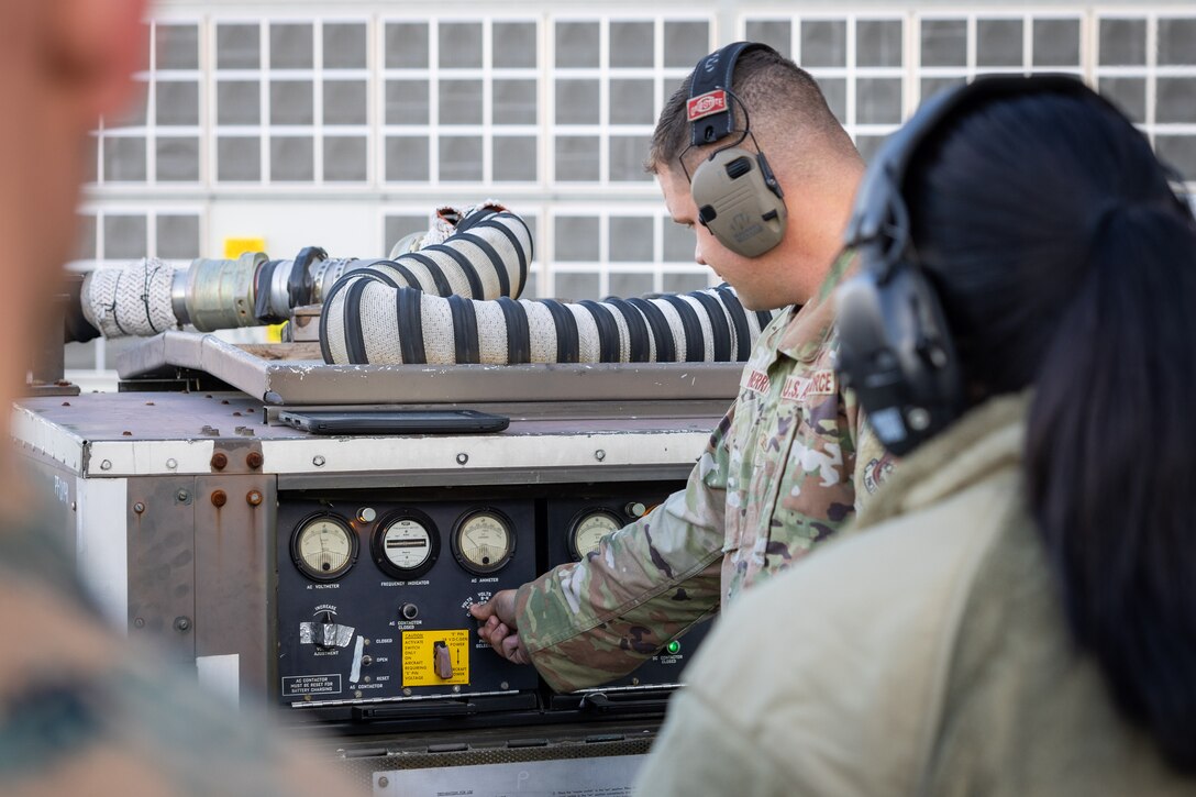 U.S. Air Force Staff Sgt. Ryan Merritt, an aerospace ground equipment specialist with the U.S. Air Force 36th Contingency Response Squadron, 36th Contingency Response Group, demonstrates how to operate an A/M32A-60A generator during a training exercise at MCAS Iwakuni, Japan, Dec. 12, 2023. The U.S. Air Force 36th Contingency Response Group conducted joint training that focused on equipment and process interoperability in a contested logistics environment with the MCAS Iwakuni Headquarters and Headquarters Squadron Logistics Department and members of the Japan Air Self-Defense Force.  (U.S. Marine Corps photo by Cpl. Darien Wright)