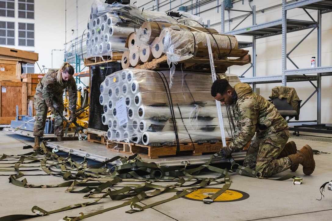 U.S. Air Force Airman 1st Class Abigail Dalton, left, and Airman Curtis Norris, both air transportation specialists with the U.S. Air Force 36th Contingency Response Squadron, 36th Contingency Response Group, demonstrate how to secure cargo during a training exercise at Marine Corps Air Station Iwakuni, Japan, Dec. 12, 2023. The U.S. Air Force 36th Contingency Response Group conducted joint training that focused on equipment and process interoperability in a contested logistics environment with the MCAS Iwakuni Headquarters and Headquarters Squadron Logistics Department and members of the Japan Air Self-Defense Force.  (U.S. Marine Corps photo by Cpl. Darien Wright)