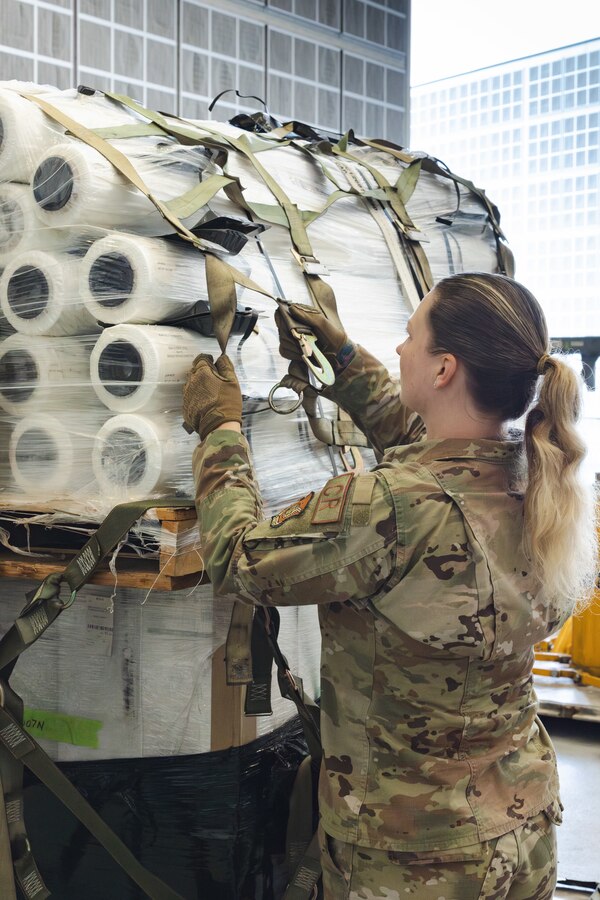 U.S. Air Force Airman 1st Class Abigail Dalton, an air transportation specialist with the U.S. Air Force 36th Contingency Response Squadron, 36th Contingency Response Group, demonstrates how to secure cargo during a training exercise at Marine Corps Air Station Iwakuni, Japan, Dec. 12, 2023. The U.S. Air Force 36th Contingency Response Group conducted joint training that focused on equipment and process interoperability in a contested logistics environment with the MCAS Iwakuni Headquarters and Headquarters Squadron Logistics Department and members of the Japan Air Self-Defense Force.  (U.S. Marine Corps photo by Cpl. Darien Wright)