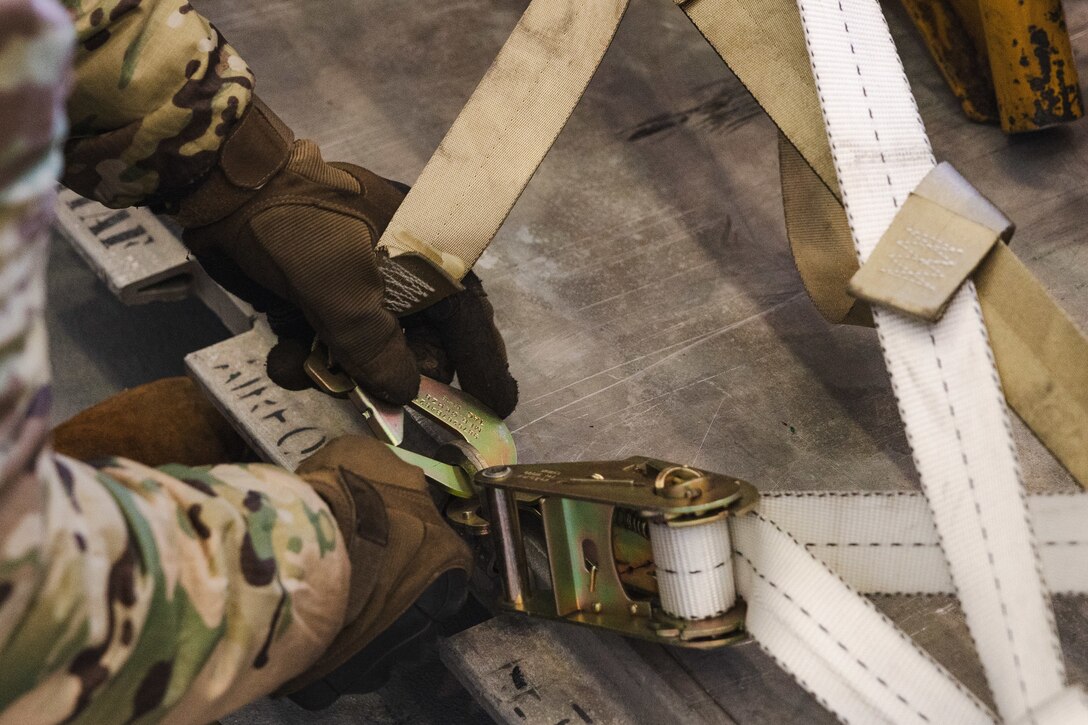 U.S. Air Force Airman Curtis Norris, an air transportation specialist with the U.S. Air Force 36th Contingency Response Squadron, 36th Contingency Response Group, demonstrates how to secure cargo during a training exercise at Marine Corps Air Station Iwakuni, Japan, Dec. 12, 2023. The U.S. Air Force 36th Contingency Response Group conducted joint training that focused on equipment and process interoperability in a contested logistics environment with the MCAS Iwakuni Headquarters and Headquarters Squadron Logistics Department and members of the Japan Air Self-Defense Force.  (U.S. Marine Corps photo by Cpl. Darien Wright)