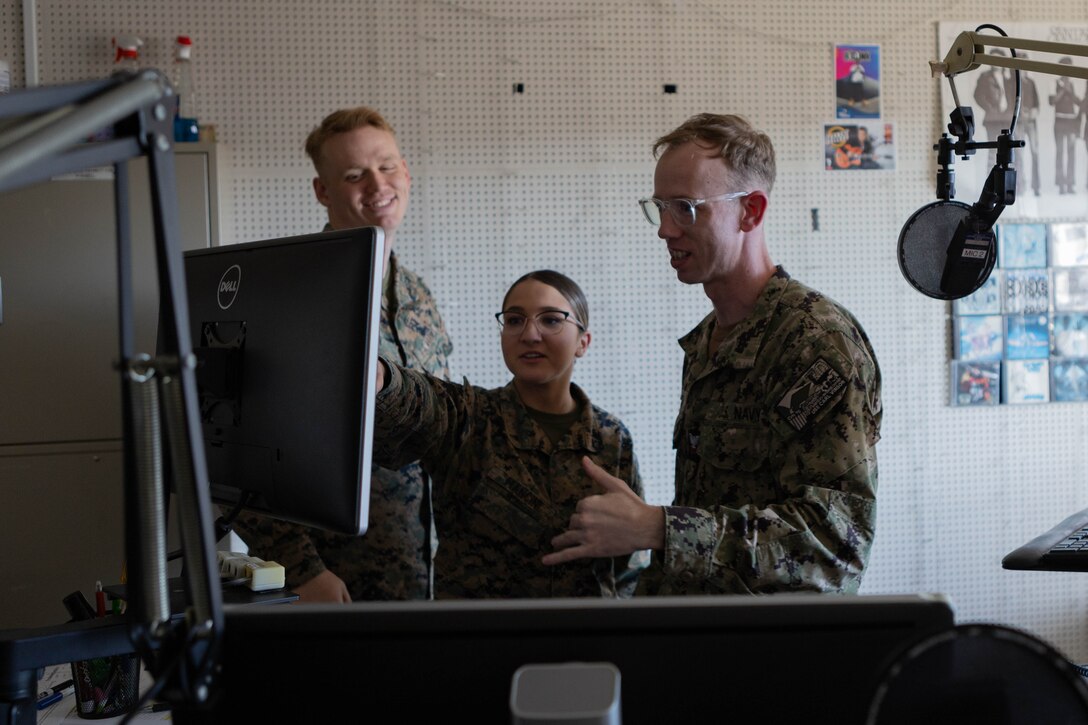 U.S. Marine Corps Lance Cpl. Brian Bolin,  left, Lance Cpl. Isabella Mancini,, center, combat photographers, and U.S. Navy Mass Communication Specialist 2nd Class Jeffery Kempton, all with Armed Forces Network Iwakuni, Defense Media Activity, talk about music requests at Marine Corps Air Station Iwakuni, Japan, Nov. 7, 2023. AFN Iwakuni broadcasts news, music, and informational commercials to entertain and inform the community about events happening on base and more.