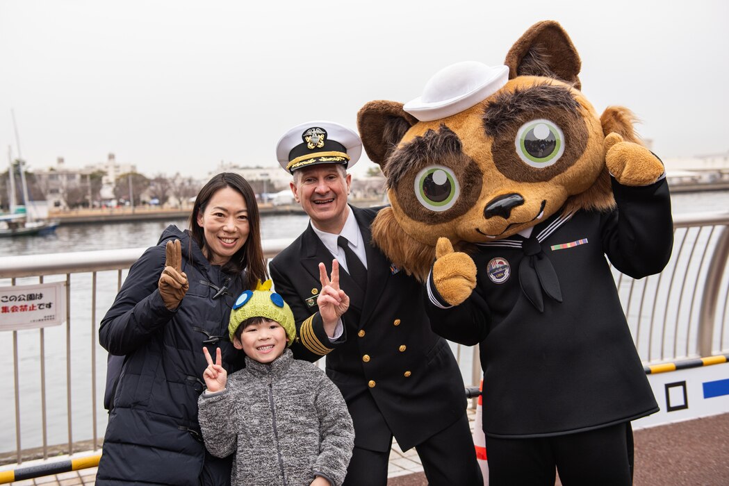 Capt. Les Sobol, Commander, Fleet Activities Yokosuka, and the installation's mascot, Yokopon, pose for a photo with two visitors during the Yokosuka Spring Festival 2024.