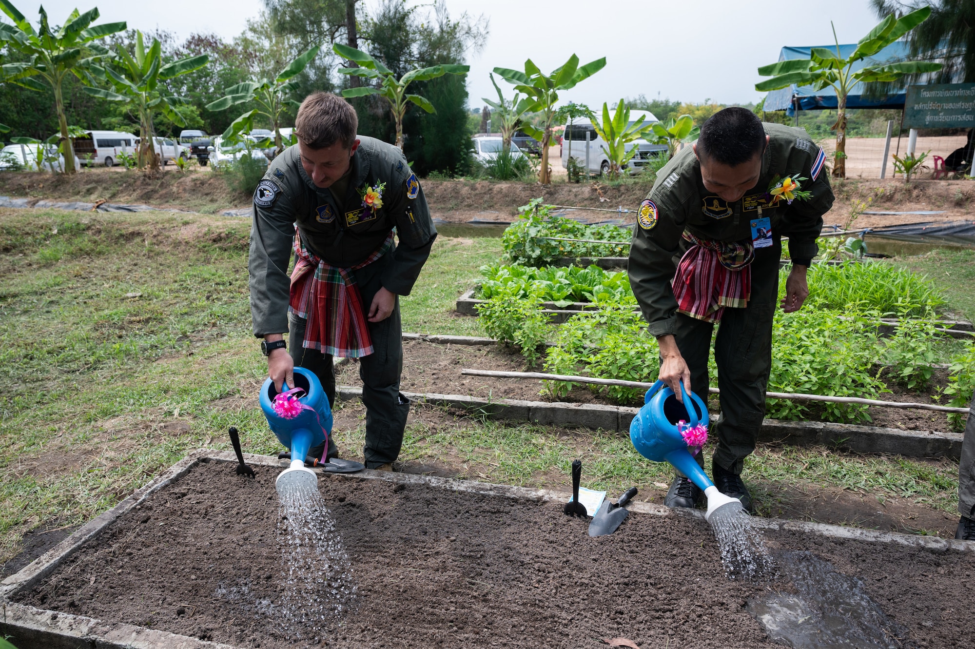 U.S. Air Force Col. Jeffrey Shulman, Cope Tiger 2024 exercise director, plants and waters seeds in the garden alongside his Royal Thai Air Force counterpart during a community outreach event for Cope Tiger 2024, Ban Krok Duan Ha School, Nakhon Ratchasima Province, Thailand, March 21, 2024. The exercise directors from the Royal Thai, Republic of Singapore and U.S. Air Force participated in a ribbon cutting ceremony for a new facility on the school campus, planted seeds in the garden, toured the school and served lunch to the students. (U.S. Air Force photo by Tech. Sgt. Hailey Haux)