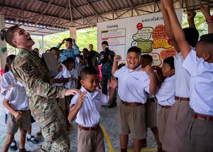 Senior Airman Jack Mitchell, 356th Fighter Generation Squadron crew chief out of Eielson Air Force Base, Alaska, plays rock, paper, scissors with students during a community outreach event for Cope Tiger 2024, Ban Krok Duan Ha School, Nakhon Ratchasima Province, Thailand, March 21, 2024. As part of the outreach event, U.S. Air Force Airmen participated in various activities like local games such as relay races, ball tosses, and a competitive game of rock, paper, scissors. (U.S. Air Force photo by Tech. Sgt. Hailey Haux)