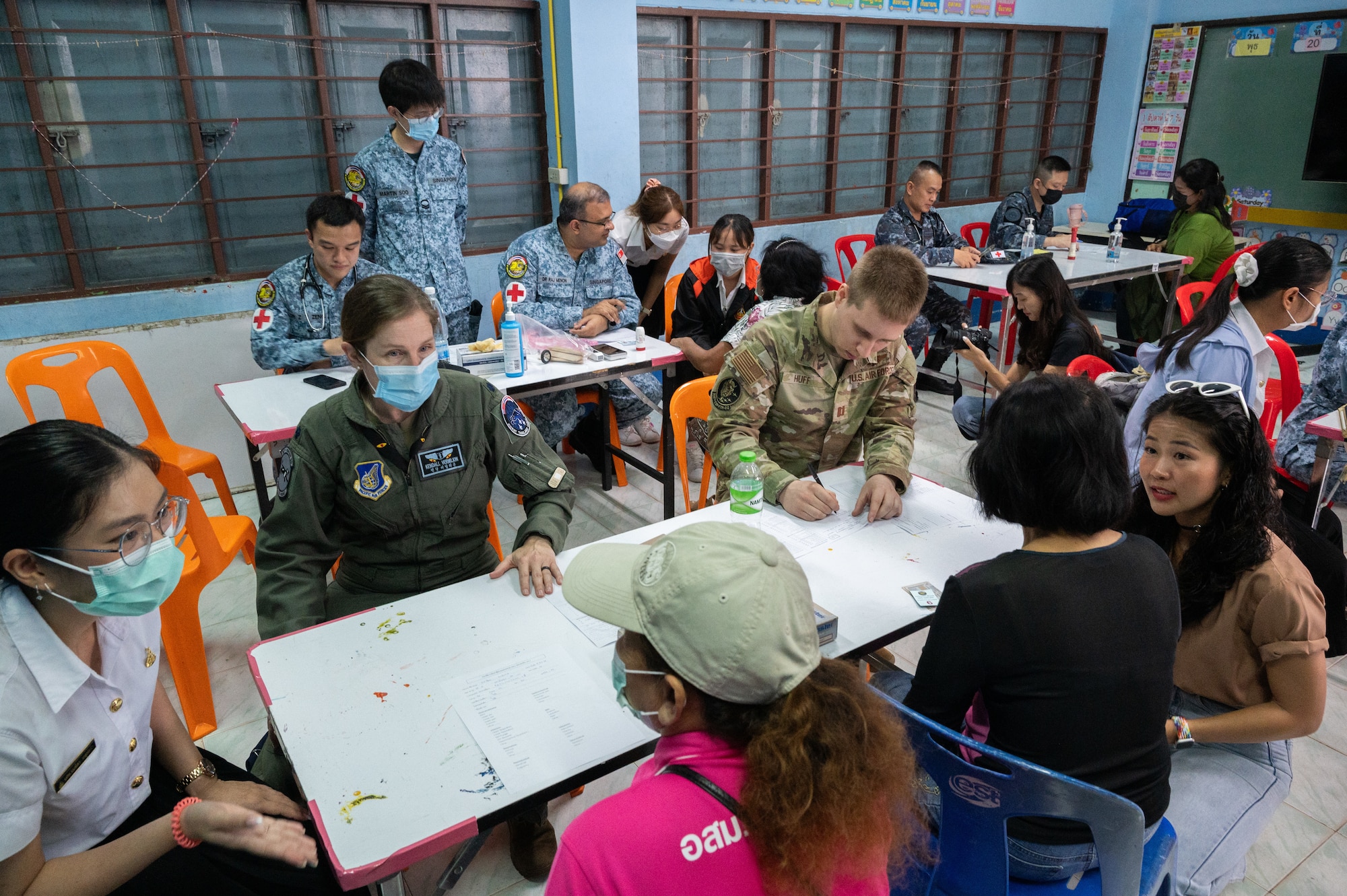 U.S. Air Force Lt. Col. Kendall Vermilion, 35th Fighter Squadron flight surgeon, and Capt. Dennis Huff, 356th Fighter Squadron flight surgeon, assist the Royal Thai Air Force and Republic of Singapore Air Force medical teams in checking patients in during a community outreach event for Cope Tiger 2024, Ban Krok Duan Ha School, Nakhon Ratchasima Province, Thailand, March 21, 2024. The event was part of Cope Tiger which is an annual trilateral aerial exercise meant to enhance readiness and further develop interoperability. (U.S. Air Force photo by Tech. Sgt. Hailey Haux)
