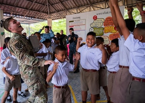 Senior Airman Jack Mitchell, 356th Fighter Generation Squadron crew chief out of Eielson Air Force Base, Alaska, plays rock, paper, scissors with students during a community outreach event for Cope Tiger 2024, Ban Krok Duan Ha School, Nakhon Ratchasima Province, Thailand, March 21, 2024. As part of the outreach event, U.S. Air Force Airmen participated in various activities like local games such as relay races, ball tosses, and a competitive game of rock, paper, scissors. (U.S. Air Force photo by Tech. Sgt. Hailey Haux)