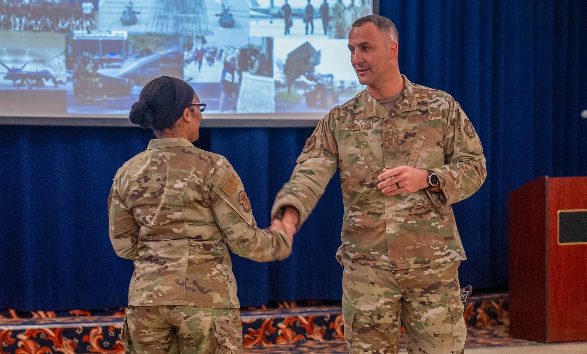 Two Airmen shake hands at a conference