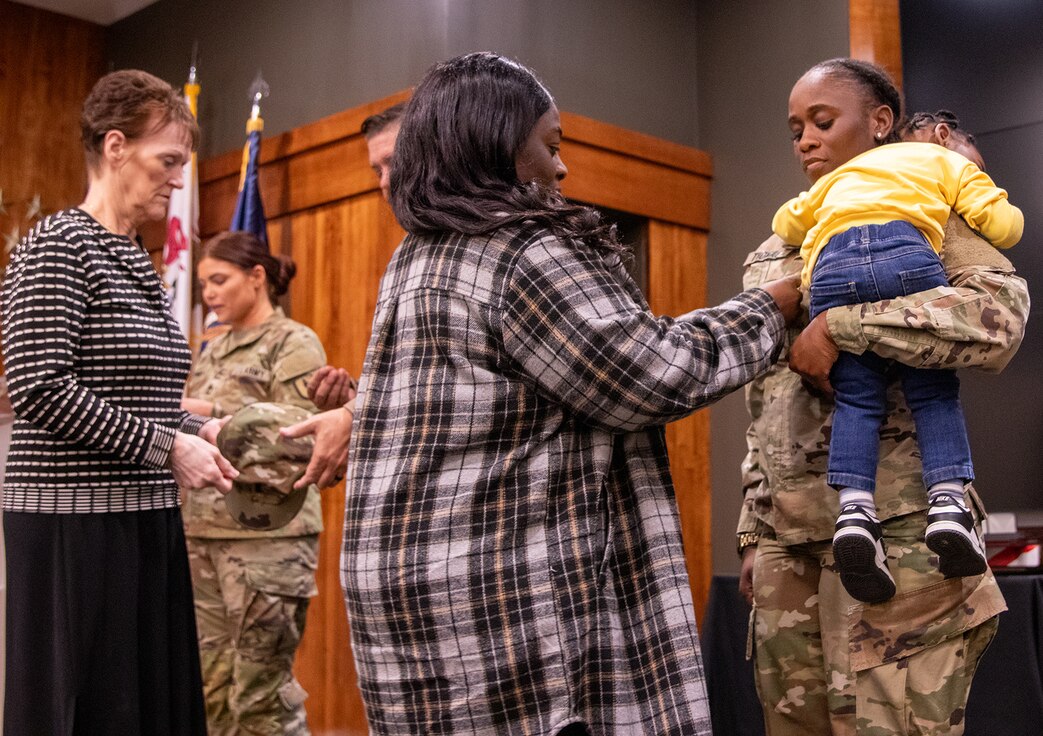 Tracy Thomas, mother of newly promoted Illinois Army National Guard Capt. Mikaya Thomas, secures new rank on Thomas’ uniform while Ernie Secrest, Thomas’ great aunt, pins new rank on her cap March 23 at the Illinois Military Academy, Camp Lincoln, Springfield.