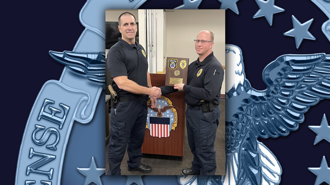 Two police officers shaking hands, one holding a plaque.