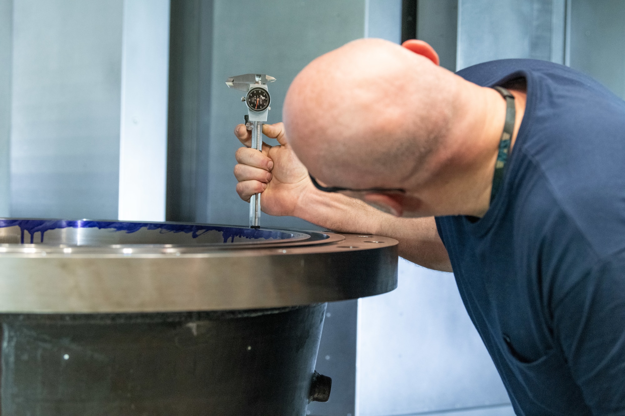 Nick Delong, a machinist in the Arnold Air Force Base Model and Machine Shop, conducts measurements on a wind tunnel nozzle following a run in the recently-acquired vertical turning center, or VTC, March 5, 2024, at Arnold AFB, Tenn. The VTC operates similarly to a wood lathe except items are situated vertically on a rotating table within the machine chamber. As the piece rotates, carbide blades within the chamber are used to mill and grind until the piece is formed into the desired shape. The VTC was needed to accelerate the fabrication of various-sized nozzles to be installed in a wind tunnel at Arnold AFB, headquarters of Arnold Engineering Development Complex. (U.S. Air Force photo by Keith Thornburgh)