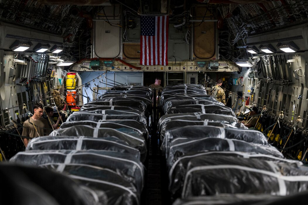 Airmen prepare humanitarian aid destined for airdrop over Gaza on an AMC C-17.