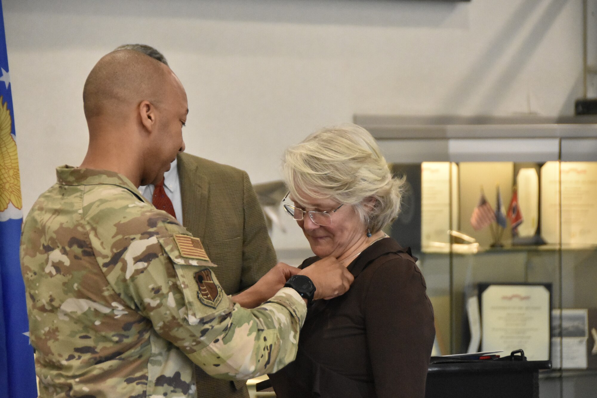 Reecie Campbell receives a lapel pin from Col. Randel Gordon, commander of Arnold Engineering Development Complex, in honor of her late brother Mike Niederhauser, March 8, 2024, at Arnold Air Force Base. Mike was named and recognized as Emeritus Honorary Commander during the Honorary Commander Induction Ceremony.