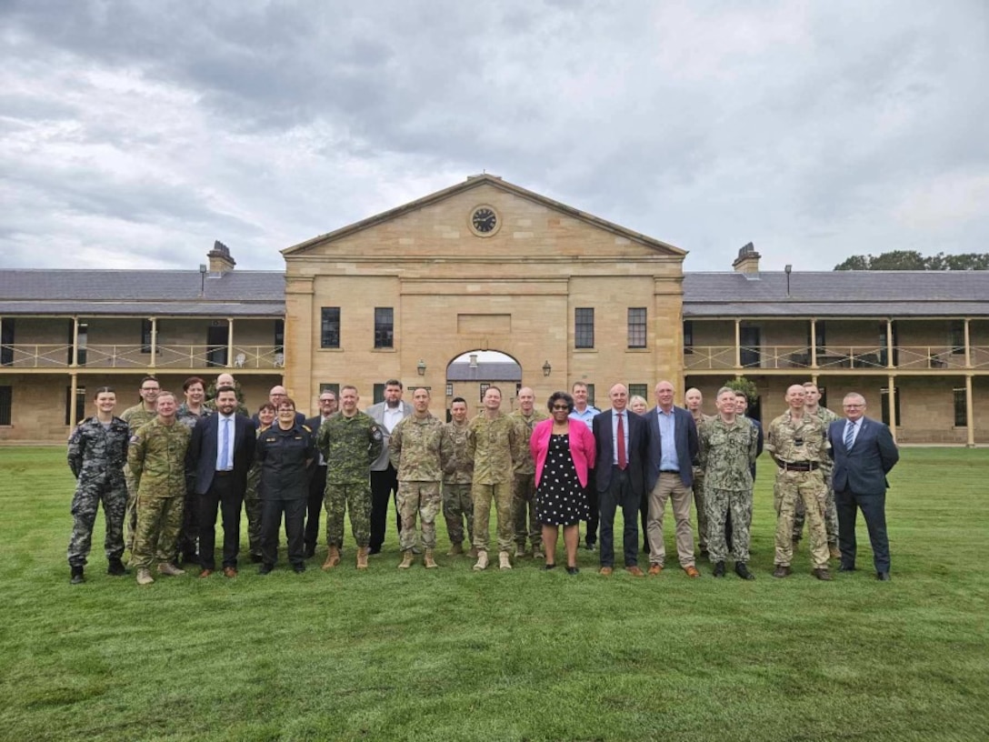 A group of men and women stand in front of a building.