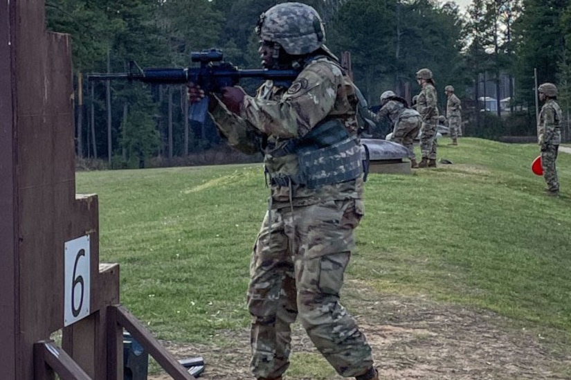 A soldier aims a weapon in a field.