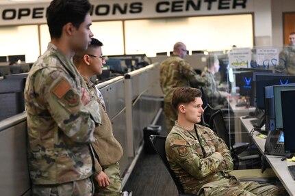 Three Airman look at a computer during exercise