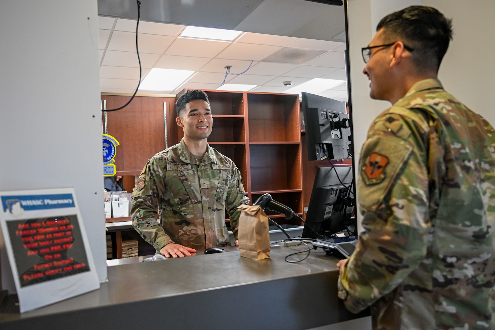 Military Pharmacy technician smiles at patient