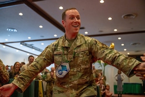 A service member reaches out his hands as he walks down to accept his award.