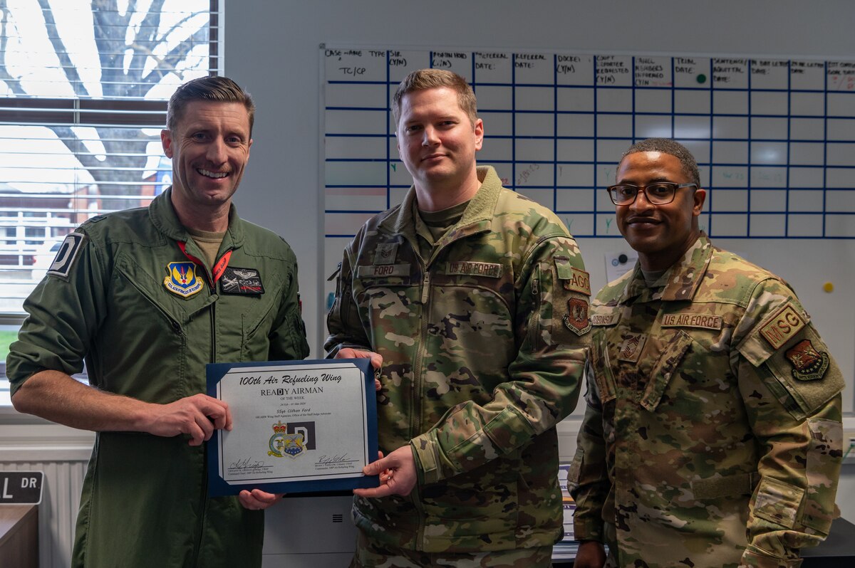 U.S. Air Force Col. Ryan Garlow, left, 100th Air Refueling Wing commander, and Chief Master Sgt. Daniel Robinson, right, 100th Mission Support Group senior enlisted leader, recognize Staff Sgt. Clifton Ford, 100th Air Refueling Wing Judge Advocate noncommissioned officer in-charge of adverse actions, as the ReaDy Airman of the Week at Royal Air Force Mildenhall, England, March 21, 2024.