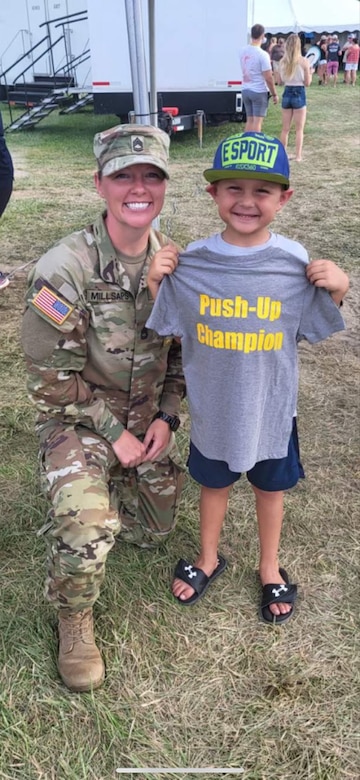 Female Soldier poses with a young boy holding a Push-Up champion t-shirt