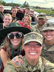 Female Soldier poses with other Soldiers, future Soldiers and civilians during a photo taken by herself