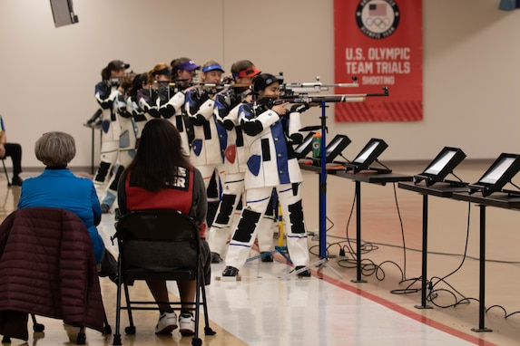 Women in shooting uniform standing with air rifle.