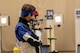 Woman in shooting uniform standing with air rifle.
