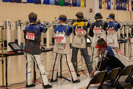 Women in shooting uniform standing with air rifle.