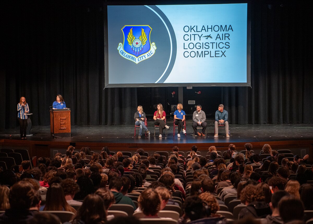 Panel members speak to high school students in an auditorium.