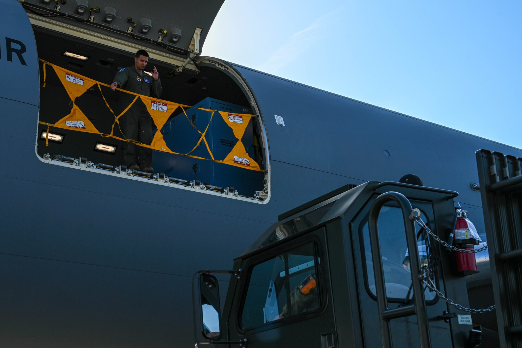 U.S. Air Force Staff Sgt. Joshua Granados, 56th Air Refueling Squadron (ARS) instructor boom operator, guides a Tunner 60K Aircraft Cargo Loader/Transporter on the flightline during Combat Cardinal 2024 at Scott Air Force Base, Illinois, March 13, 2024. This was the first time the 56th ARS supported an aeromedical evacuation training, providing a unique opportunity for the instructor pilots and boom operators. (U.S. Air Force photo by Senior Airman Trenton Jancze)