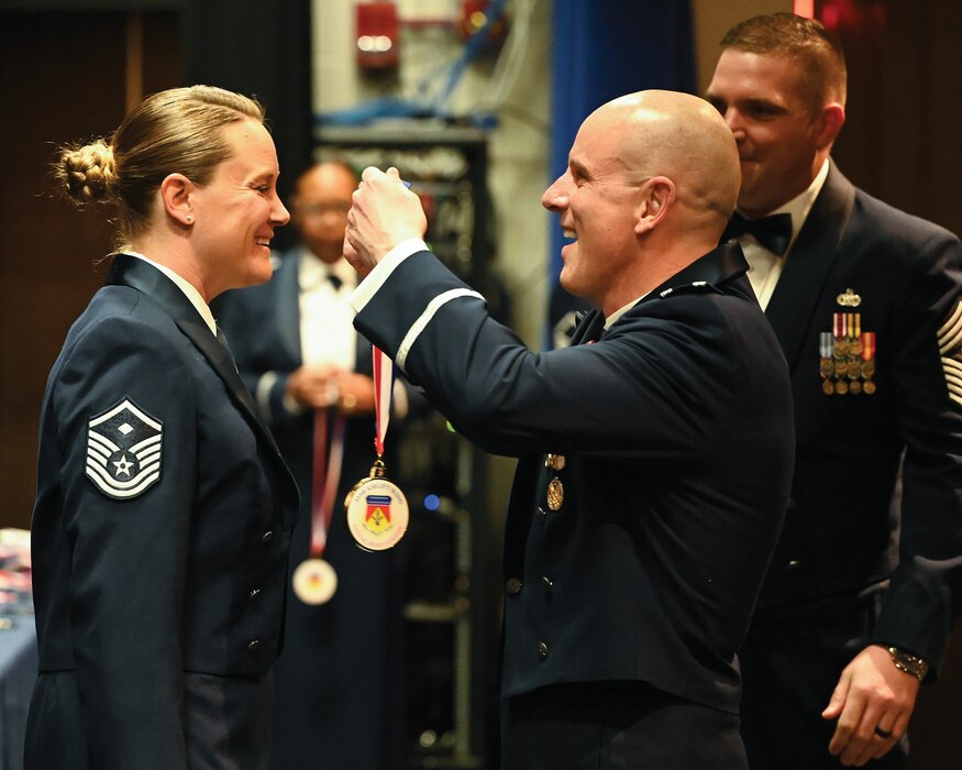 Col. Matthew Muha, 445th Airlift Wing deputy commander, presents a 445th Airlift Wing medallion to Master Sgt. Kerri Schutte, 445th Aeromedical Staging Squadron first sergeant, a nominee for First Sergeant of the Year, during the 445th AW Medallion ceremony March 9, 2024. About 50 Airmen and family members were honored at the medallion ceremony held prior to the wing's awards banquet. Col. Muha presented each nominee in attendance with a medallion.