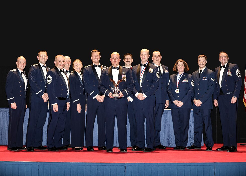 Members of the 89th Airlift Squadron, 445th Airlift Wing's 2023 Squadron of the Year, pose for a photo with Col. Matthew Muha, 445th Airlift Wing deputy commander, and Chief Master Sgt. Gordon Wager, 445th AW command chief, during the wing’s annual awards banquet at the National Museum of the U.S. Air Force, March 9, 2024. (U.S. Air Force photo/Senior Airman Angela Jackson)