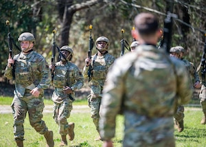 A training instructor watches trainees perform combat movements.