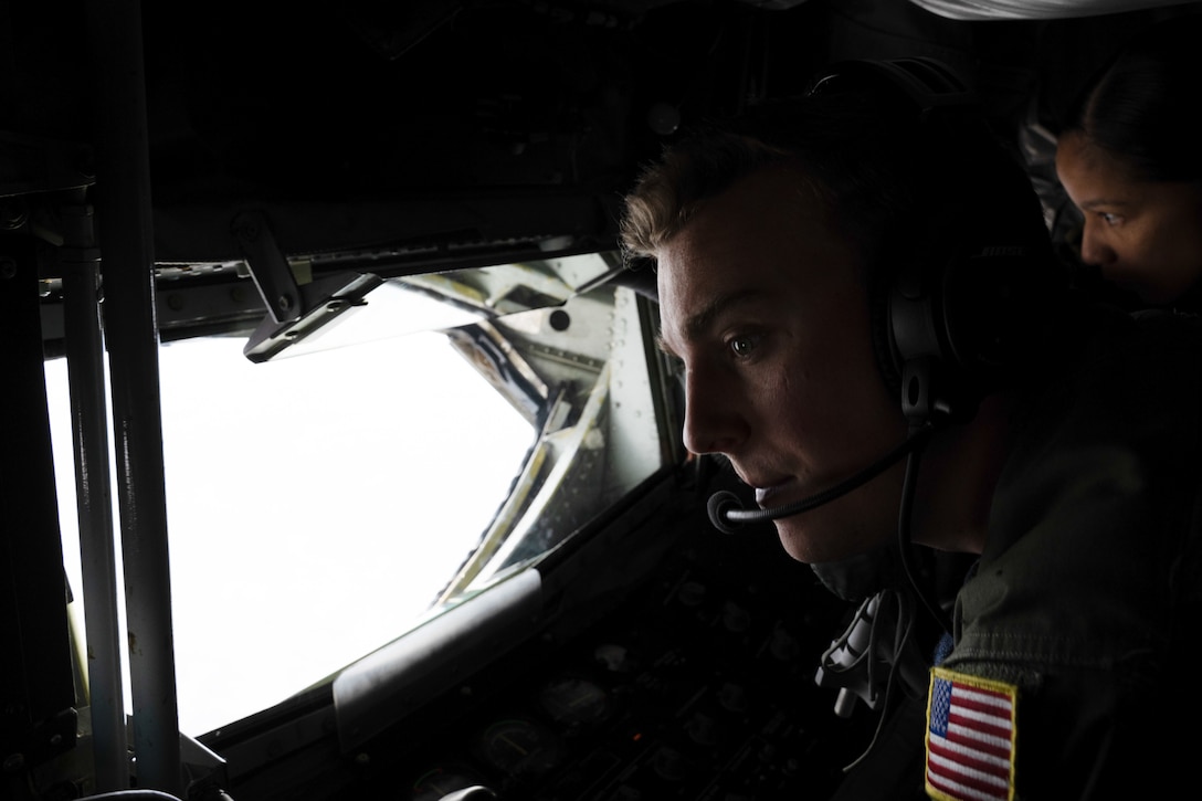 A boom operator operating the boom while another military member watches.