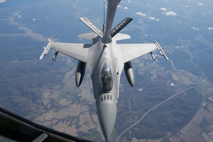 A jet flying and receiving fuel from another aircraft.