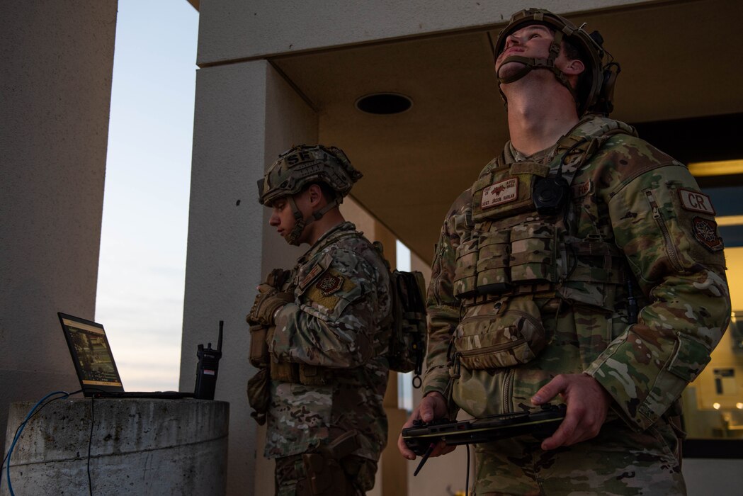 Airman watches video feed while another monitors a drone.