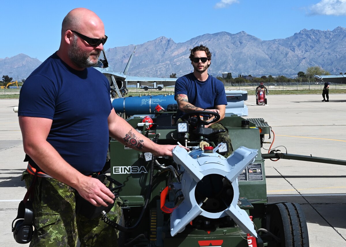 Royal Canadian air force Master Cpl. Denis, left, and Cpl. Bandeira, right, 425th Tactical Fighter Squadron air weapons system technicians, loads a bomb during Exercise Cougar South at Davis-Monthan Air Force Base, Ariz., March 14, 2024. DM supported the RCAF, which strengthened the Northern Atlantic Treaty Organization. (U.S. Air Force photo by Staff Sgt. Abbey Rieves)