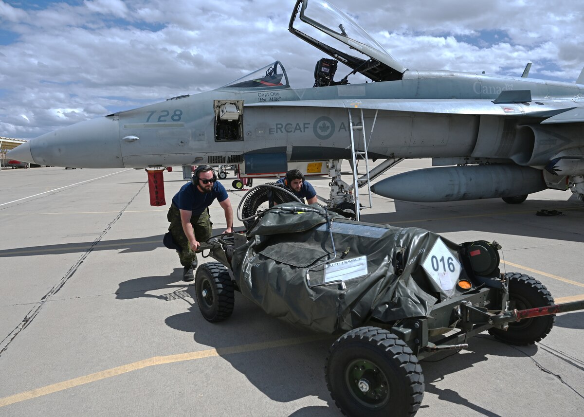 Royal Canadian air force air weapons system technicians assigned to the 425th Tactical Fighter Squadron, prepare to arm a CF-18 Hornet aircraft during Exercise Cougar South at Davis-Monthan Air Force Base, Ariz., March 14, 2024. DM maintains warfighter capabilities through international lethality and readiness training. (U.S. Air Force photo by Staff Sgt. Abbey Rieves)