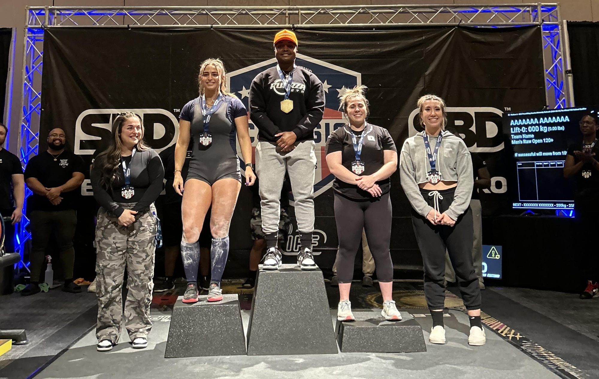 Tech. Sgt. Tiffany Savage stands at the center of the photo among other women powerlifters after competing in the 2024 Powerlifting America Nationals.